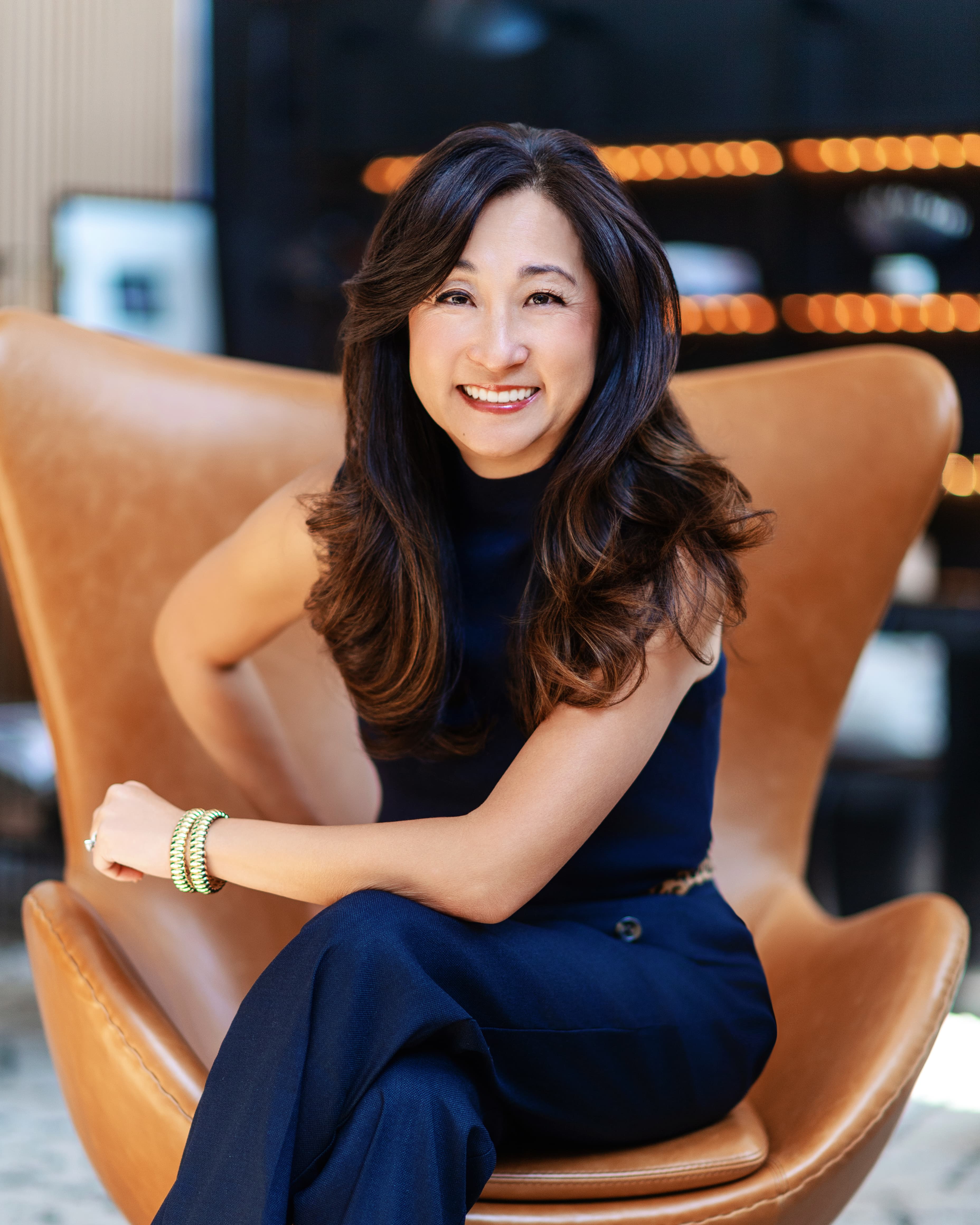 Jenny Jun seated in a tan chair